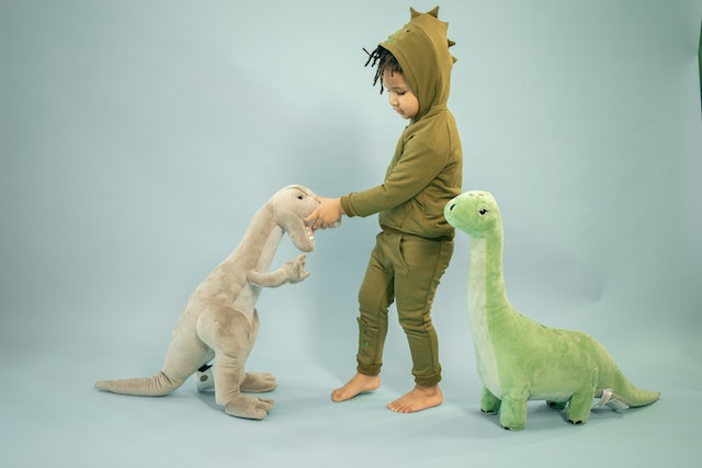 little-black-boy-with-hairstyle-playing-with-toy-dinosaur